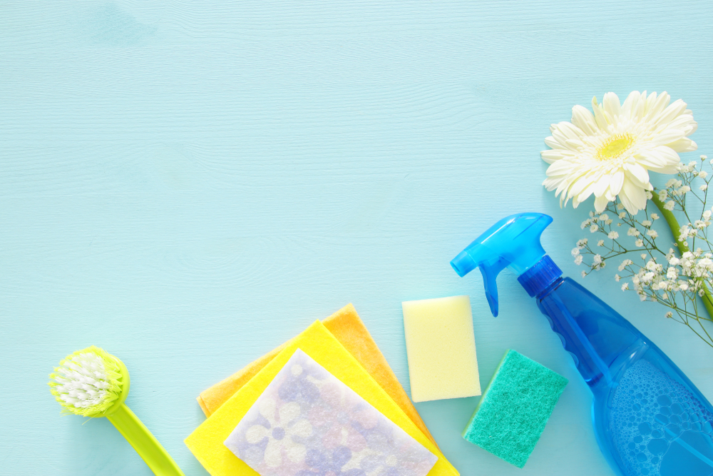 Productos de limpieza y desinfección del hogar en fondo azul cielo.